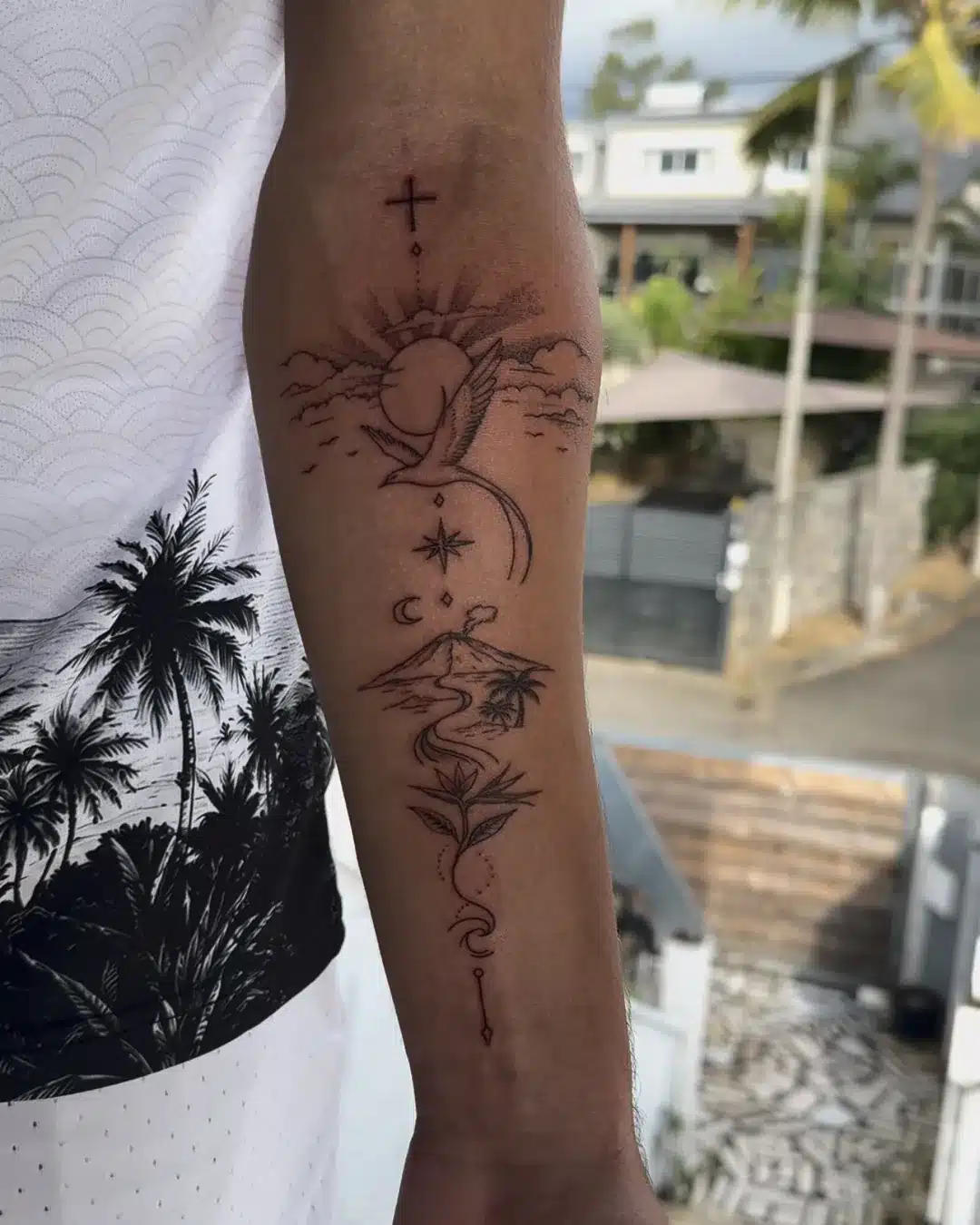 Tatouage fine line sur l'avant-bras : soleil, paille-en-queue, volcan, rivière et oiseau de paradis