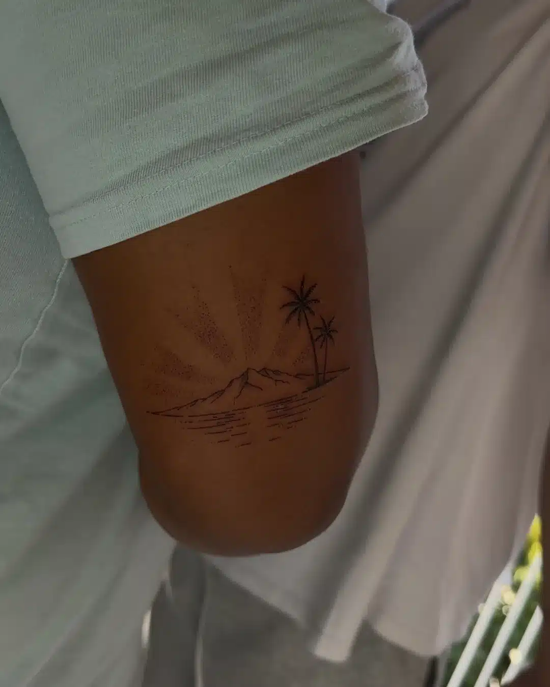 Tatouage souvenir fine line d'un paysage de La Réunion avec palmiers, montagne et soleil