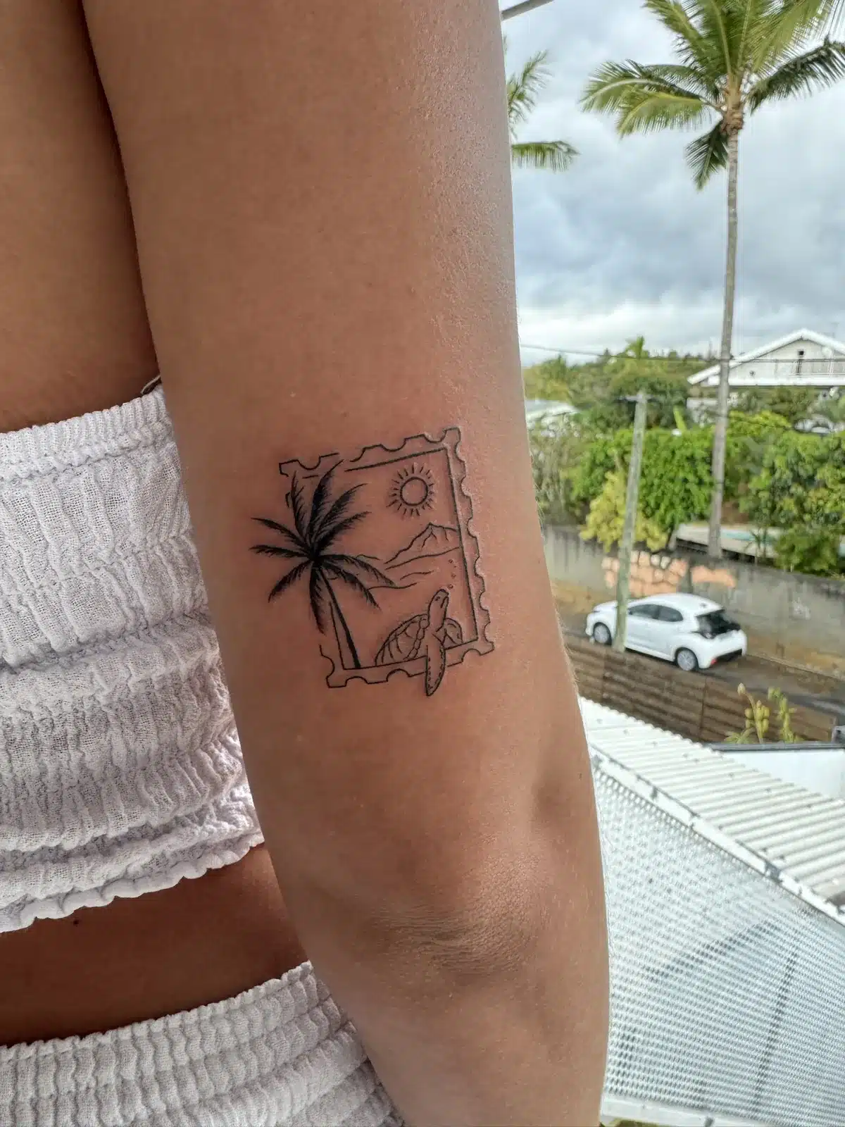 Tatouage fine line timbre de La Réunion avec tortue et palmier sur le bras – Jax Ink Tattoo, Saint-Gilles-les-Hauts