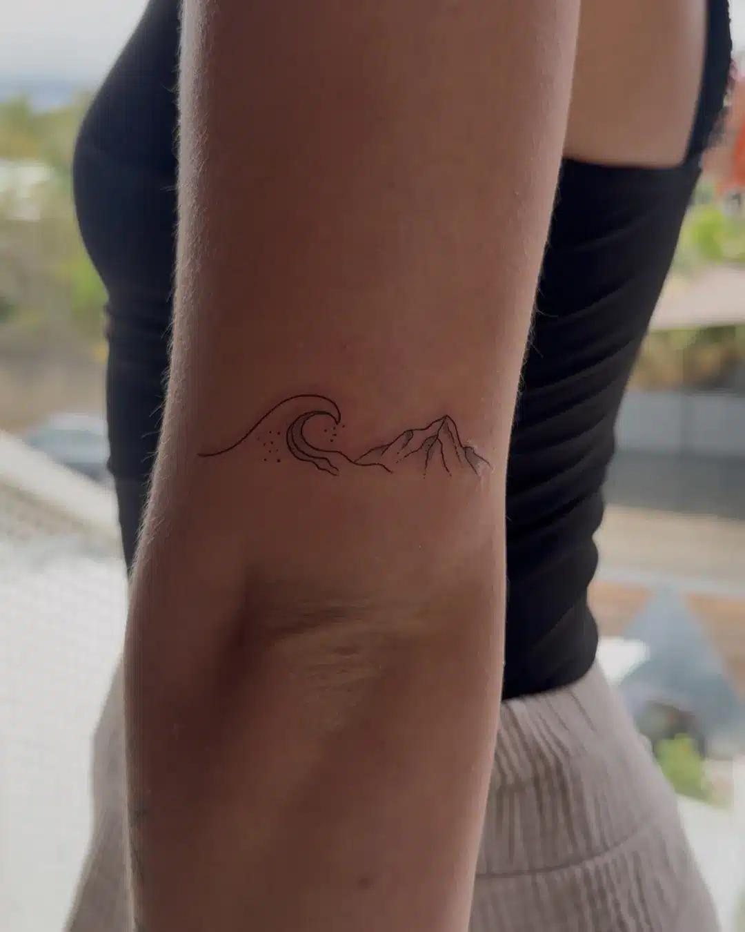 Tatouage fine line d'une vague et d'une montagne, souvenir de La Réunion